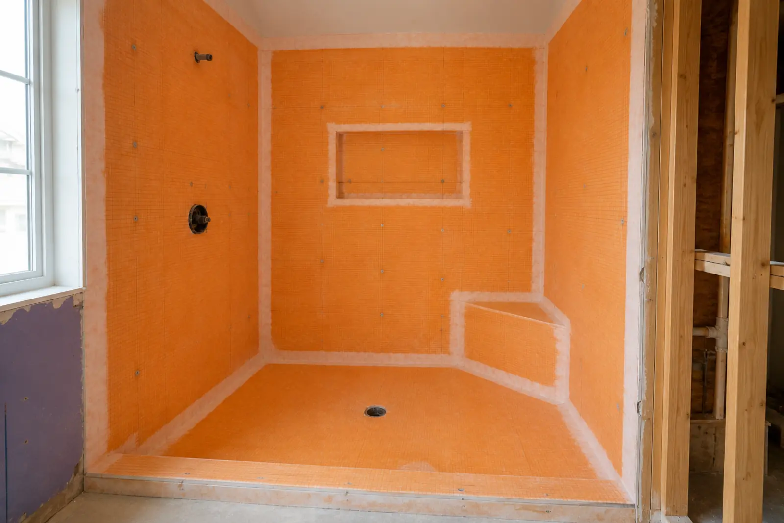 Waterproofing membrane with taped seams over a sloped shower pan before tiling